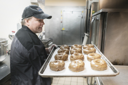Bruce Sowles, 53, of Flint, carries a tray of fresh donuts to prepare them for delivery at Blueline Donuts, inside of Carriage Town Ministries.