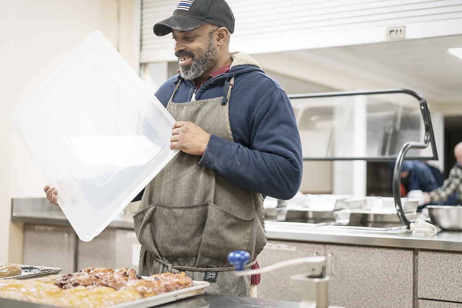 Randall Thompson, 50, of Flint, smiles as he covers up fresh donuts for delivery at Blueline Donuts inside Carriage Town Ministries.