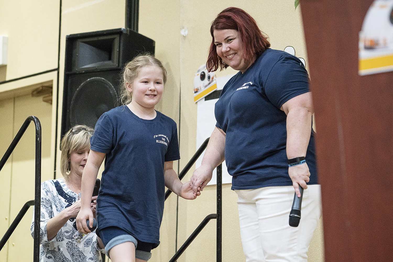 Flint, MI - Friday, May 4, 2018: FlintSide publisher Marjory Raymer (right), 44, from Flint, holds the hand of Davison Central Elementary School student Brooke Laine as she makes her way up the steps to the stage during the 5th Annual Blueberry Ambas