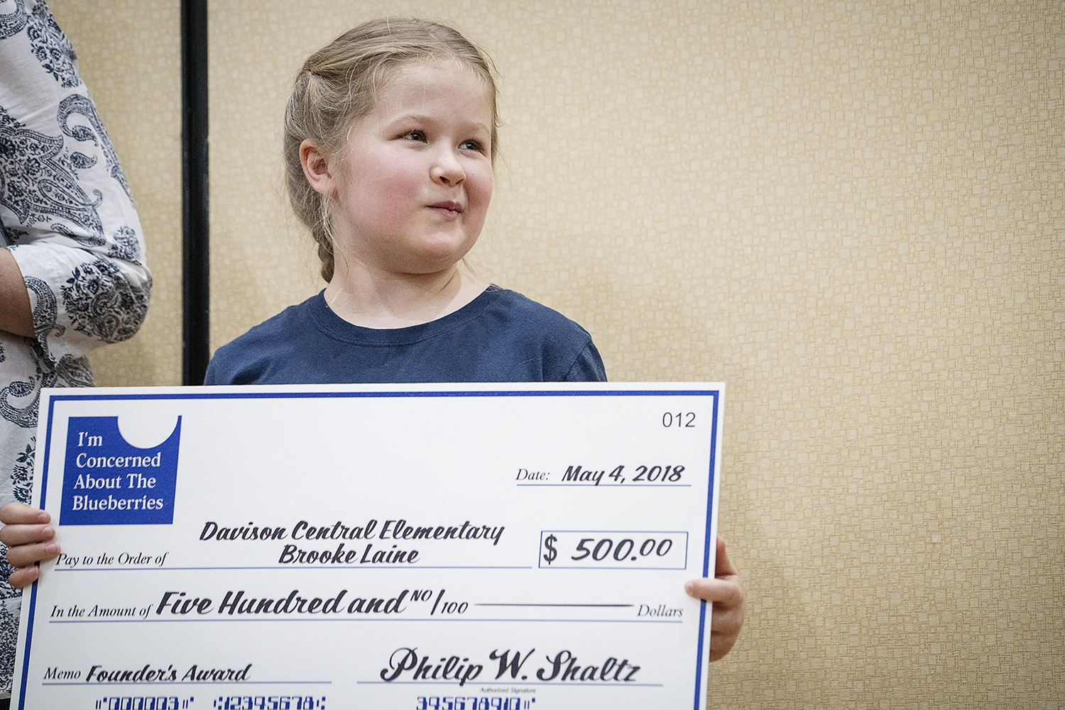 Flint, MI - Friday, May 4, 2018: Davison Central Elementary  student Brooke Laine holds a large check on stage after being presented with the Blueberry Ambassador Founder's Award during the 5th Annual Blueberry Ambassador Awards Party at the Riverfro