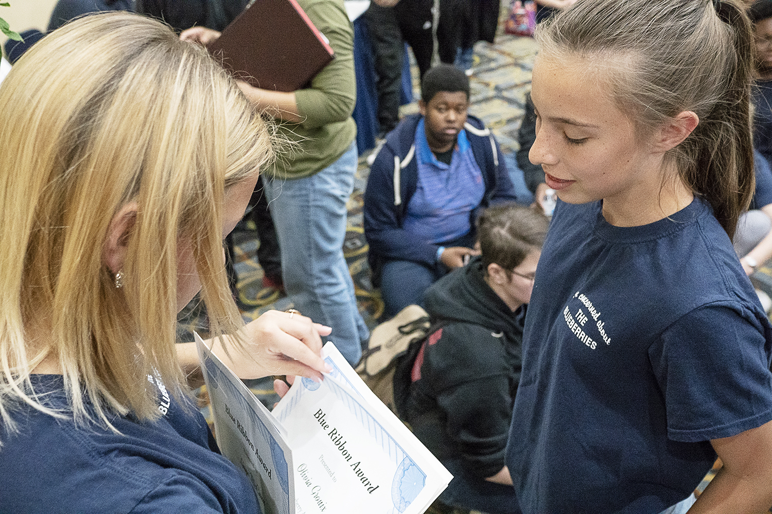 Flint, MI - Friday, May 4, 2018: University of Michigan - Flint student Carryn White, 19, from Burton hands out a Blue Ribbon Award to Olivia Grouix, a student at Flushing Middle School, during the 5th Annual Blueberry Ambassador Awards Party at the 
