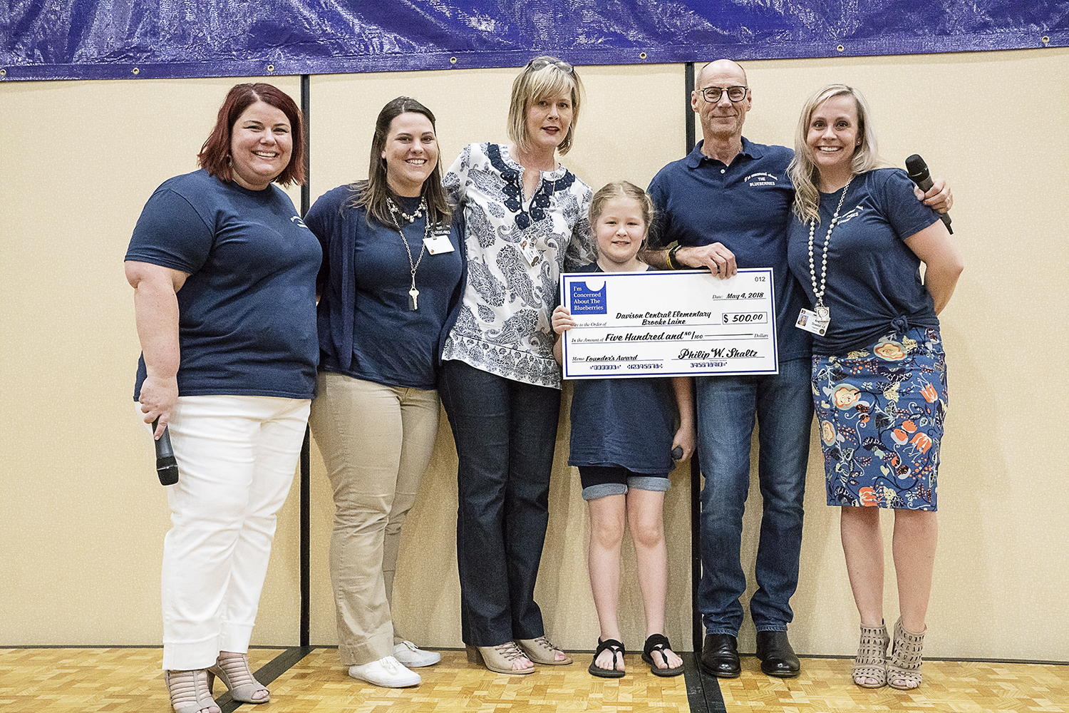 Flint, MI - Friday, May 4, 2018: Surrounded by family, teachers and Blueberry staff, Davison Central Elementary School student Brooke Laine holds a large check after being presented with the Blueberry Ambassador Founder's Award during the 5th Annual 