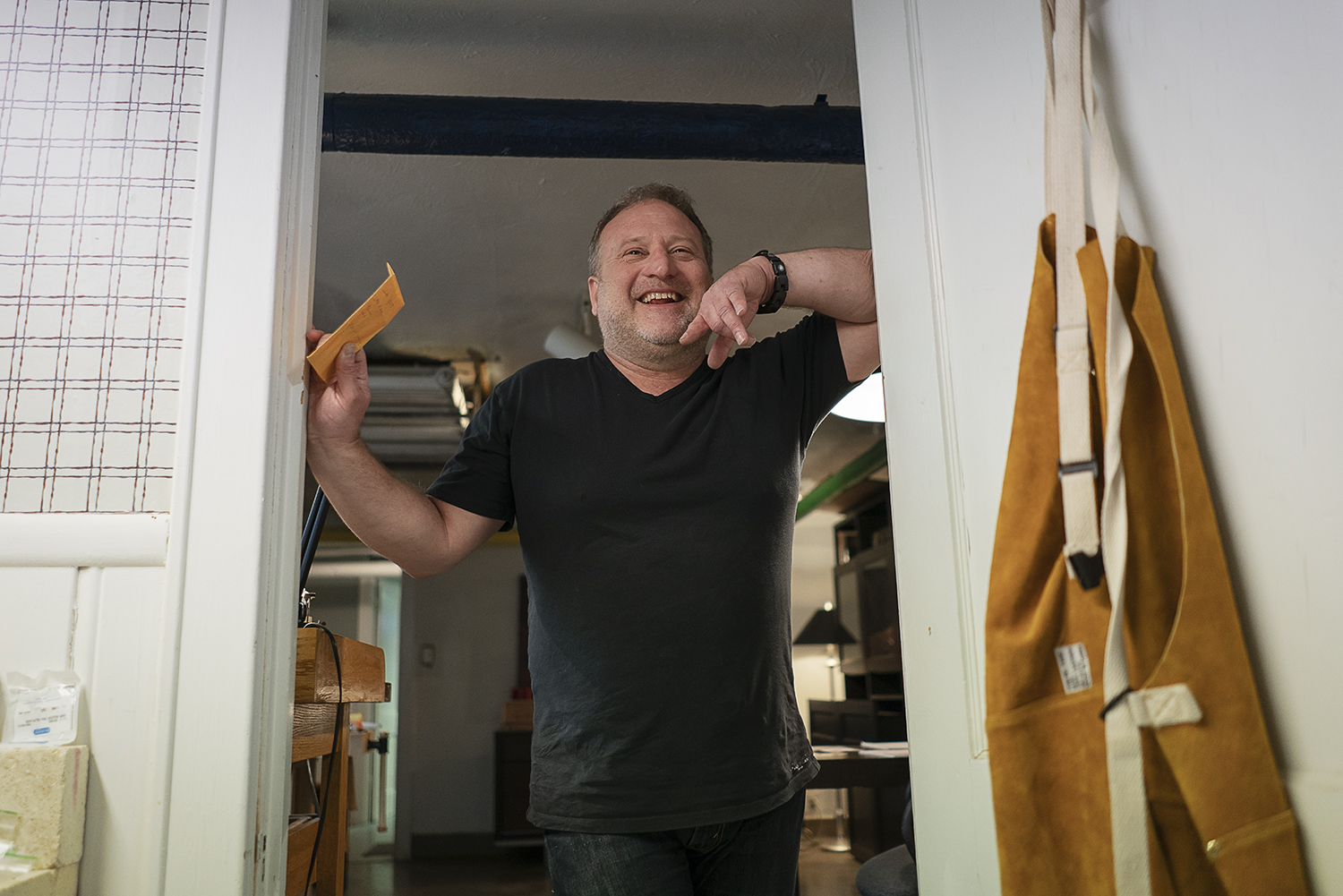 Flint, MI - Tuesday, May 8, 2018: Flint resident and metalsmith Robert McAdow laughs as he leans on the doorway to his soldering area in his studio.