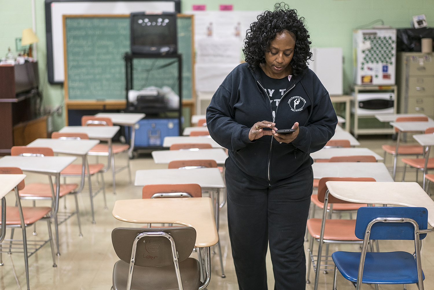 Walking between rows of empty desks in her classroom at Flint Northwestern High School, Sheila Miller-Graham checks her phone for messages before putting away homecoming decorations. Between teaching at Flint Northwestern and running Creative Express