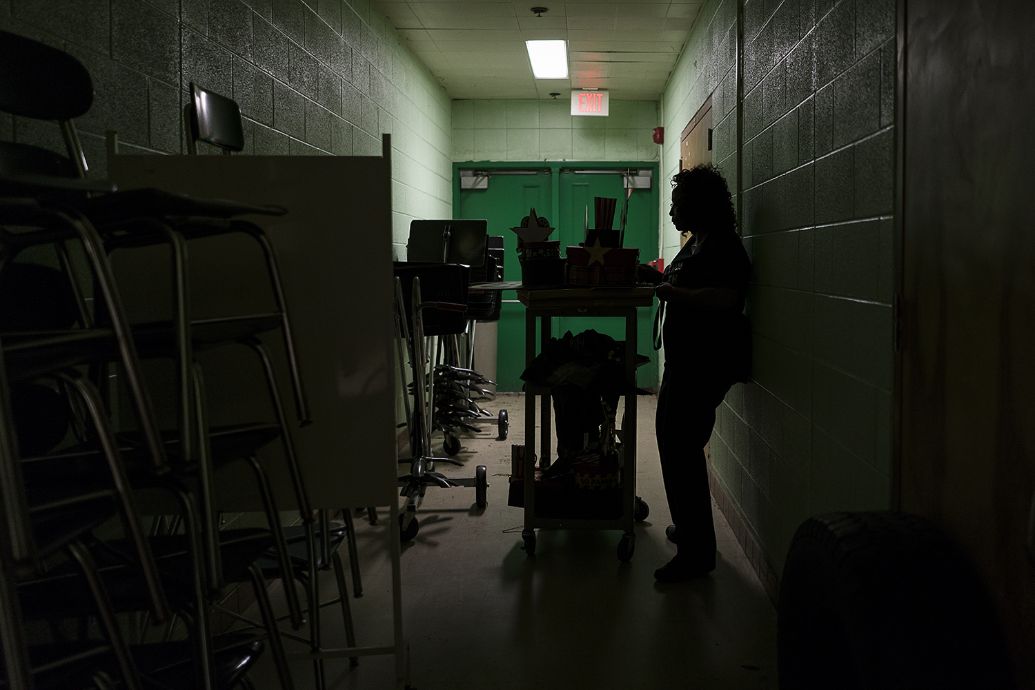 In a dimly lit corridor between the band room and auditorium at Flint Northwestern High School, Sheila Miller-Graham stands by her cart loaded with decorations for homecoming. 