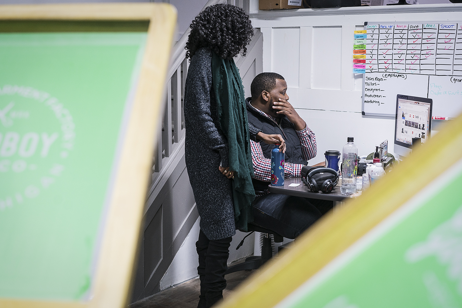 GoodBoy Clothing creator and owner Oaklin Mixon, 34, of Flint, right and public relations specialist Lydia Seale, 23, of Flint look at Mixon's monitor as they plan social media and web releases of visuals in the production area of the new GoodBoy Clo