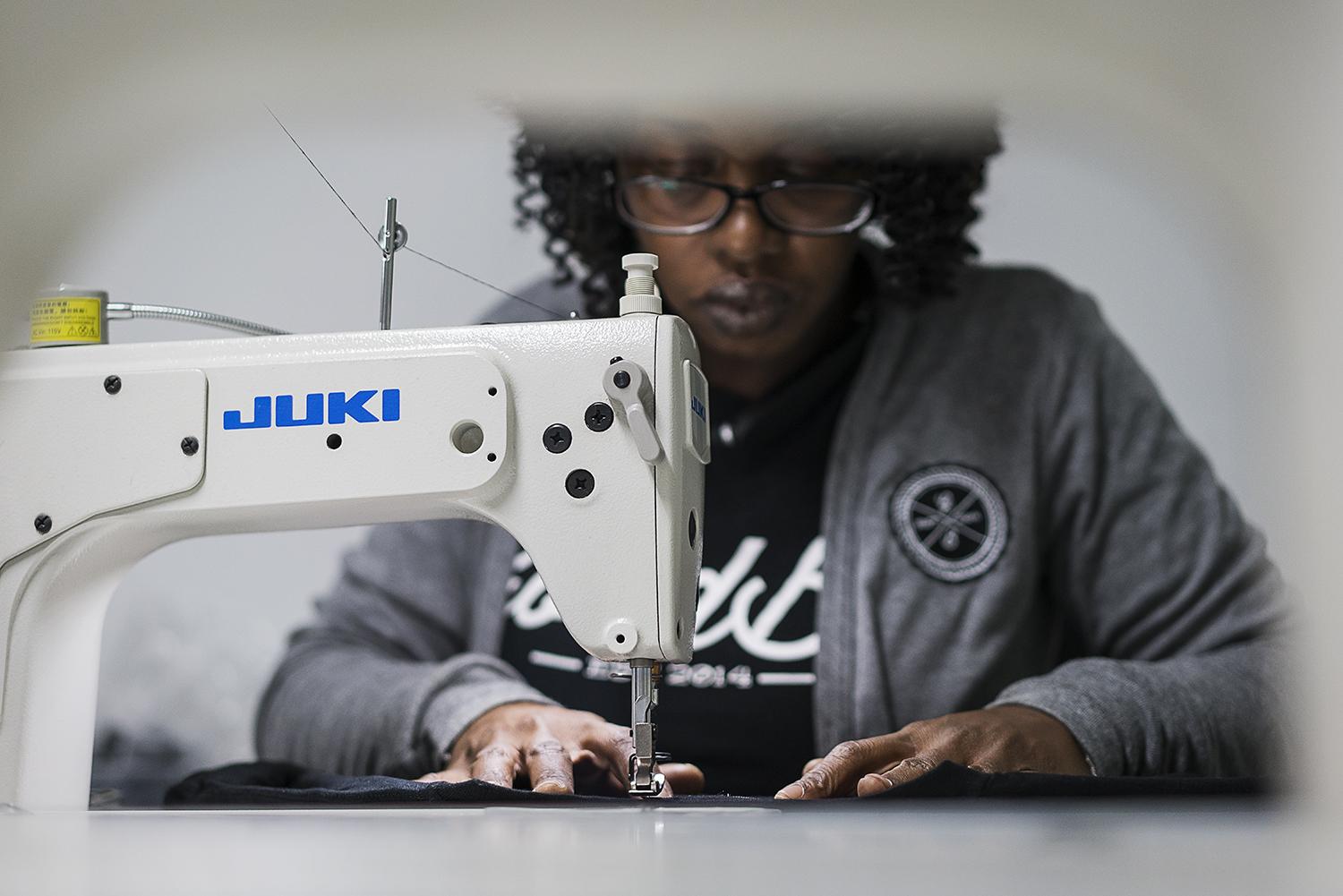 GoodBoy Clothing textile expert Tameka Davis, 37, of Flint, stitches tags into new shirts that are headed to the showroom at the new GoodBoy Clothing storefront in downtown Flint.
