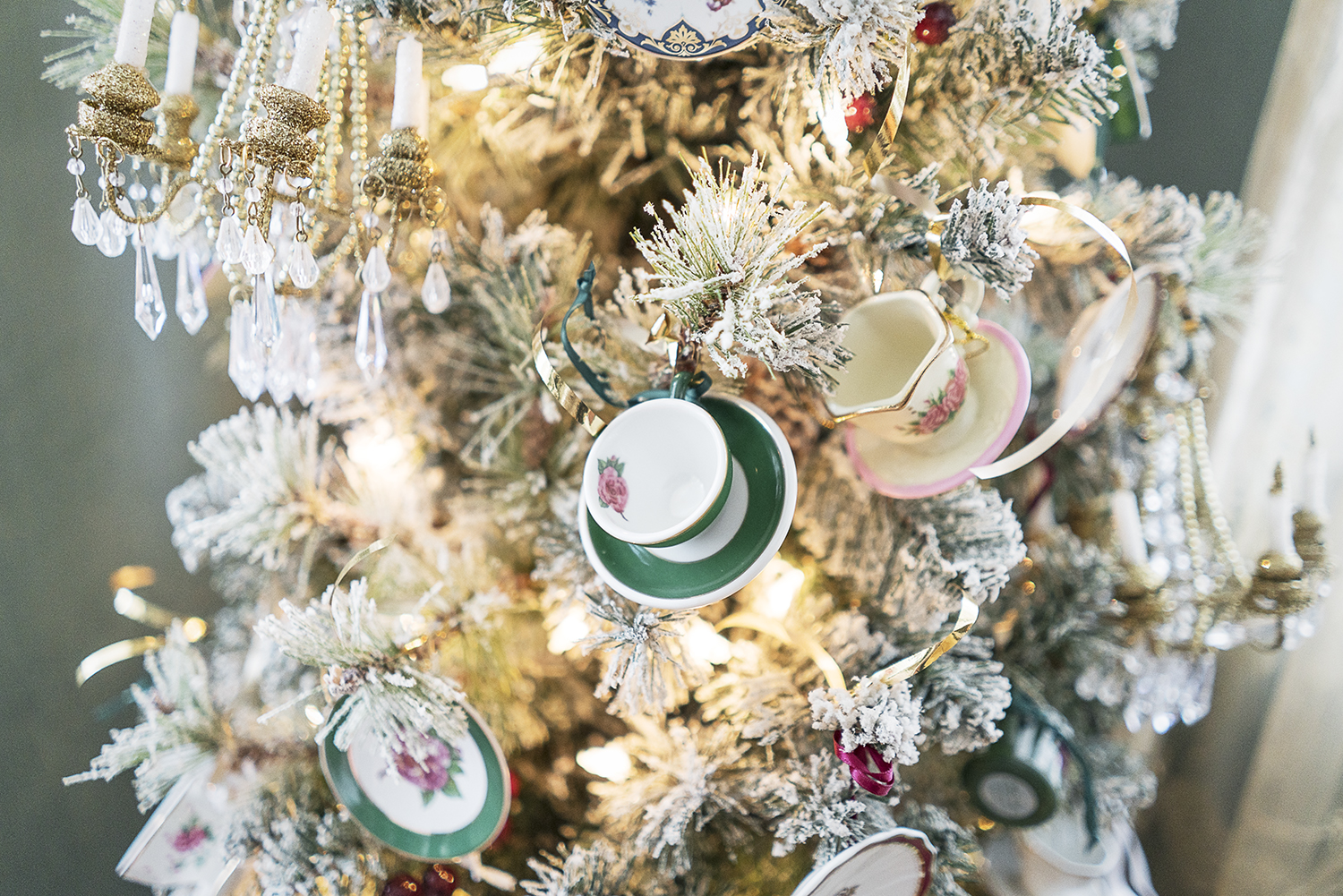 A small Christmas tree decorated with miniature tea cups and saucers sits in the corner of a room in the Heddy home.