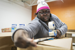 Jacquece Dent, 38, of Flint, tapes a large box full of food for a family holiday meal before it is loaded up and shipped out from the Food Bank of Eastern Michigan.