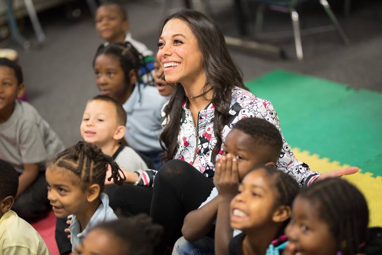 Alejandra Matos poses for a photo with children at Doyle-Ryder Elementary School in Flint