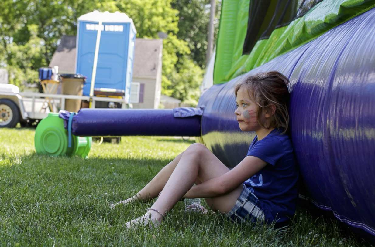 Milah Riley takes a rest outside of a bounce house on June 5.