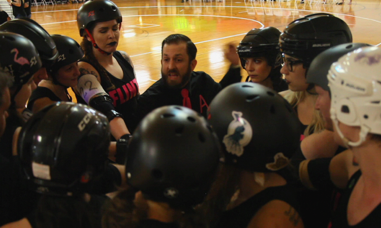 Nicholas Cotton (center) has been in love with the sport since the late 90s and came on as Flint Roller Derby head coach in 2010. 