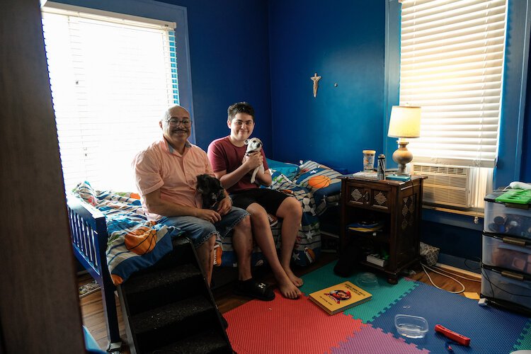 Ricky Reyes, 61, sits in his childhood bedroom that now belongs to his grandson Enrique Reyes (seated on the right).