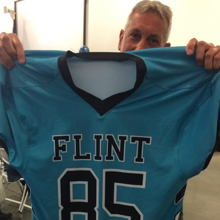 Flint Community Schools athletic director Jamie Foster shows off the look of the new unified Flint sports teams—which will be called the Jaguars.