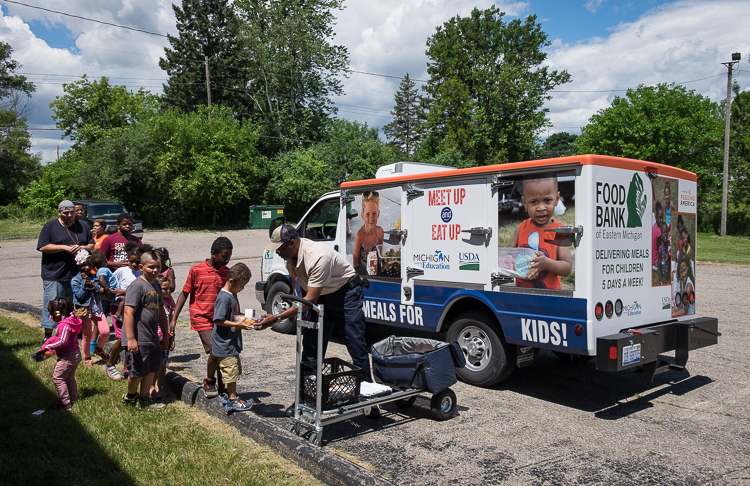 Samuel Berry Sr. distributes meals to children in a summer program at the Beecher-Vera B. Rison Library in Mt. Morris Township.  It is one of seven stops per day for Berrry.  There were 33 meals distributed at this location on this day.