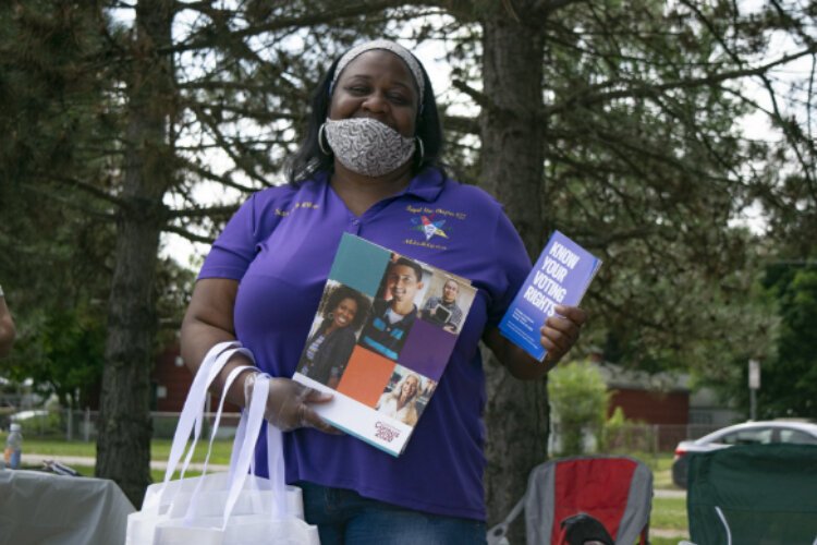 Holly Wilson from the Neighborhood Engagement Hub holds up reading material being handed out to all community members who attended the drive-thru event.