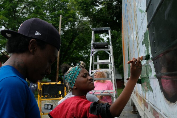 Aniyah Colston, 13, focuses on her measured strokes on the water distribution trailer mural.