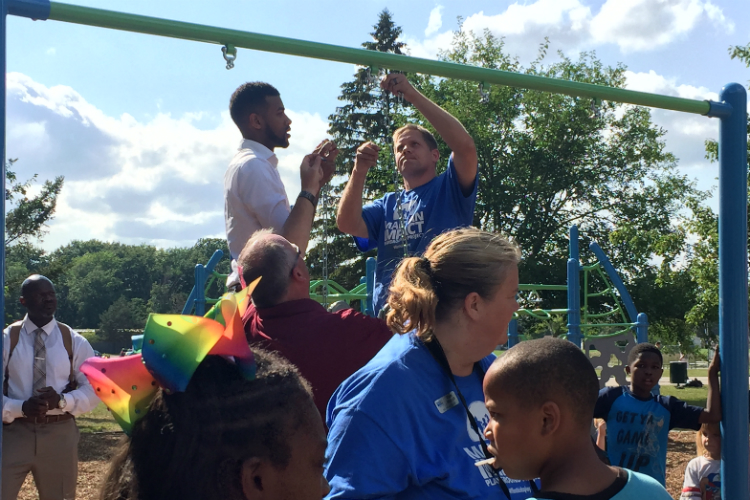 Isaiah Oliver, president of the Community Foundation of Greater Flint, (standing left) at the new playground opened Tuesday at Hasselbring Senior Center.
