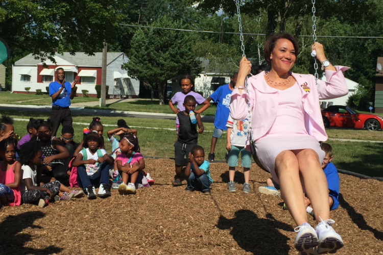 Flint Mayor Karen Weaver tries out the swings installed as part of the new playground at Hasselbring Senior Center.