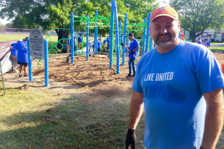 Jamie Gaskin, United Way of Genesee County CEO, helps oversee the work at the playground build Tuesday at Hasselbring Senior Center.