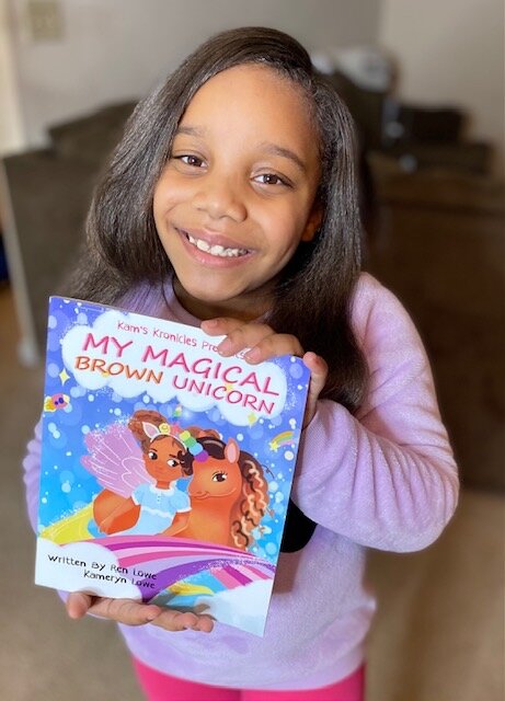Kameryn Lowe holding up a copy of 'My Magical Brown Unicorn.'