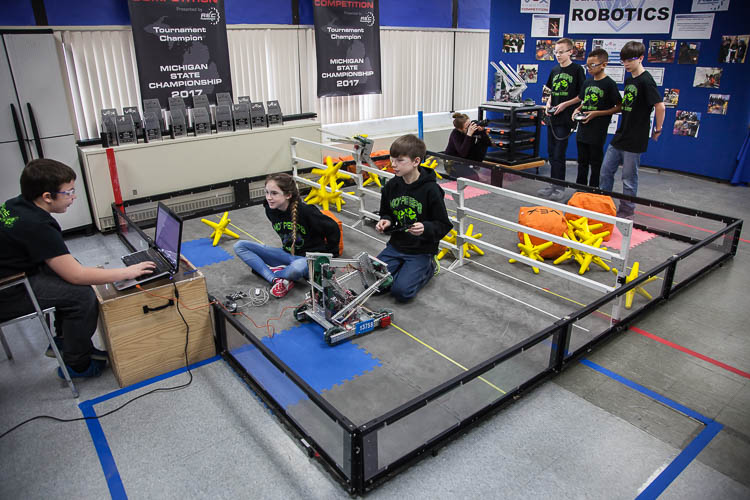 Parker Oosterhof, 12 (left); Lydia Minzey, 12; and Alex Wickham, 13, (right) work to program a robot for competition. In background are Caleb Rose, 13, (left); Micah Shamly, 12; and Jack Roy, 12, (right) who demonstrate driving the robot and picking 