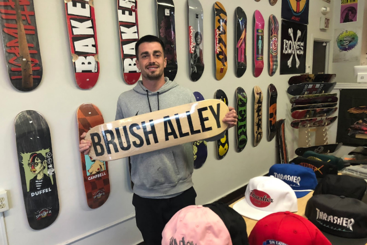 Jennings Harper, owner of Brush Alley Skateshop, shows off the new custom boards available at his shop, located at 111 E. Third St. in downtown Flint.