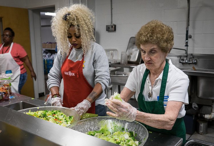 Employee Monica Campbell of Flint, left, and volunteer Sarah Massimino of Mt. Morris Township assemble salad for the free lunch that will be offered at St. Luke N.E.W. Life Center.