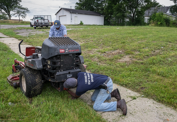 Hurb Pitts puts a belt back on a mower for Deacon Darris Berry at Shiloh Missionary Baptist Church. 