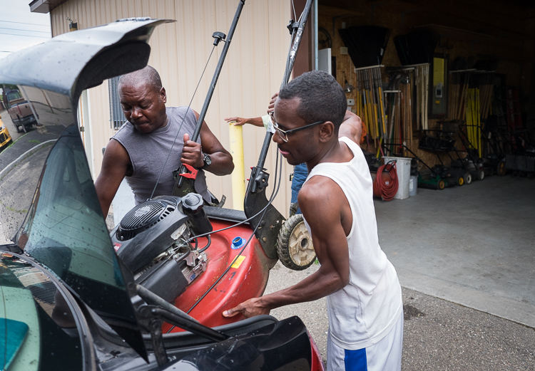 Earl Murry (left) helps Tameceo Weems load a lawn mower into his trunk at the Community Tool Shed.