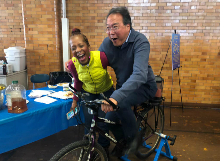 Yo-Yo Ma mixes it up with Angela Stamps on her bike-powered blender. Notice the smoothie being created over the back tire.