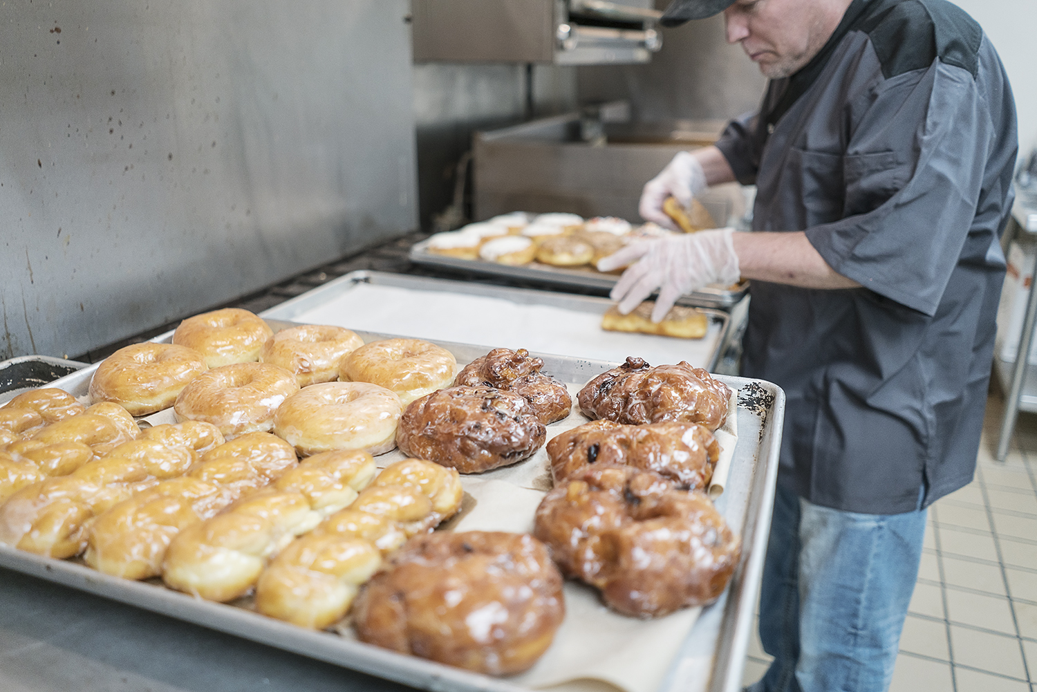 Bruce Sowles, 53, of Flint, transfers donuts to baking sheets before they are delivered to Foster's Coffee in downtown Flint at Blueline Donuts inside of Carriage Town Ministries.