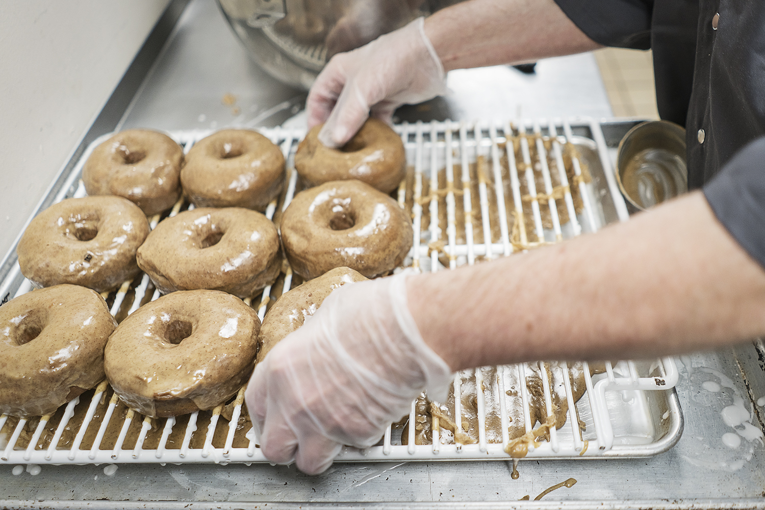 Bruce Sowles, 53, of Flint, transfers donuts to baking sheets before they are delivered to Foster's Coffee in downtown Flint at Blueline Donuts inside of Carriage Town Ministries. 