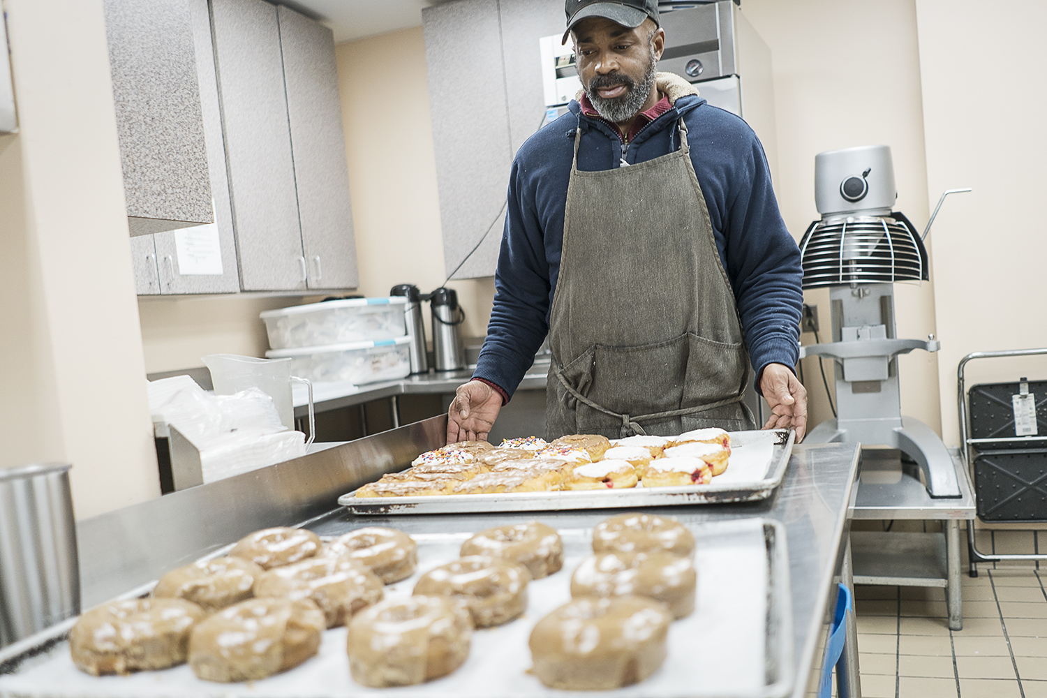 Randall Thompson, 50, of Flint, adjusts trays of fresh donuts in preparation for delivery to Foster's Coffee in downtown Flint, at Blueline Donuts inside Carriage Town Ministries.