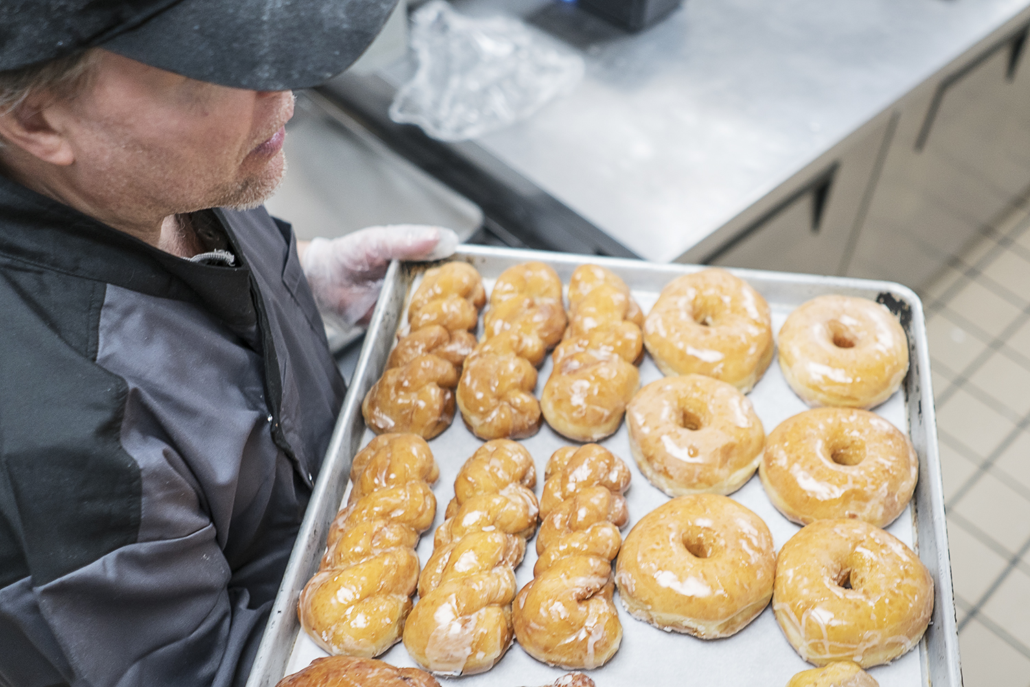 Bruce Sowles, 53, of Flint, carries a tray of fresh donuts to prepare them for delivery at Blueline Donuts, inside of Carriage Town Ministries.