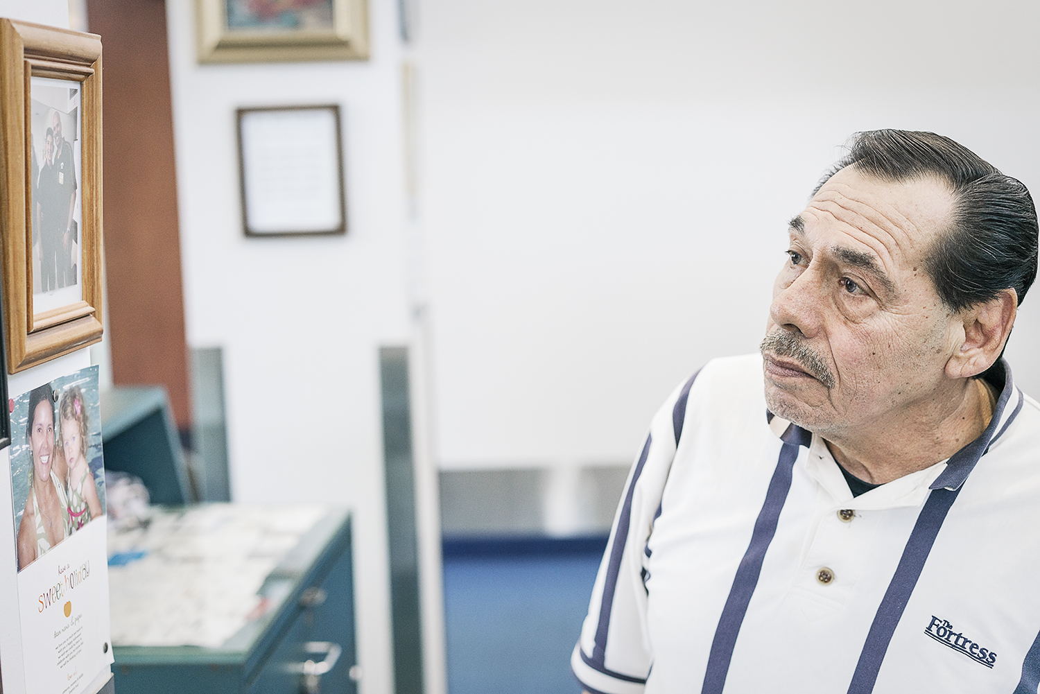 Flint, MI - Friday, January 26, 2018: Joe Garza, 69, from Mt. Morris, looks at photographs of his family that hang on the walls of the shoe shine stand at Bishop International Airport, where he has worked for 36 years.