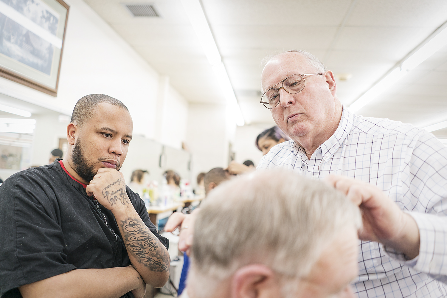 Flint, MI - Tuesday, February 6, 2018: Instructor Larry Woodby, 70, from Linden (right), examines a customer's cut by barber Chris Hampton, 29, from Flint, at the Flint Institute of Barbering.