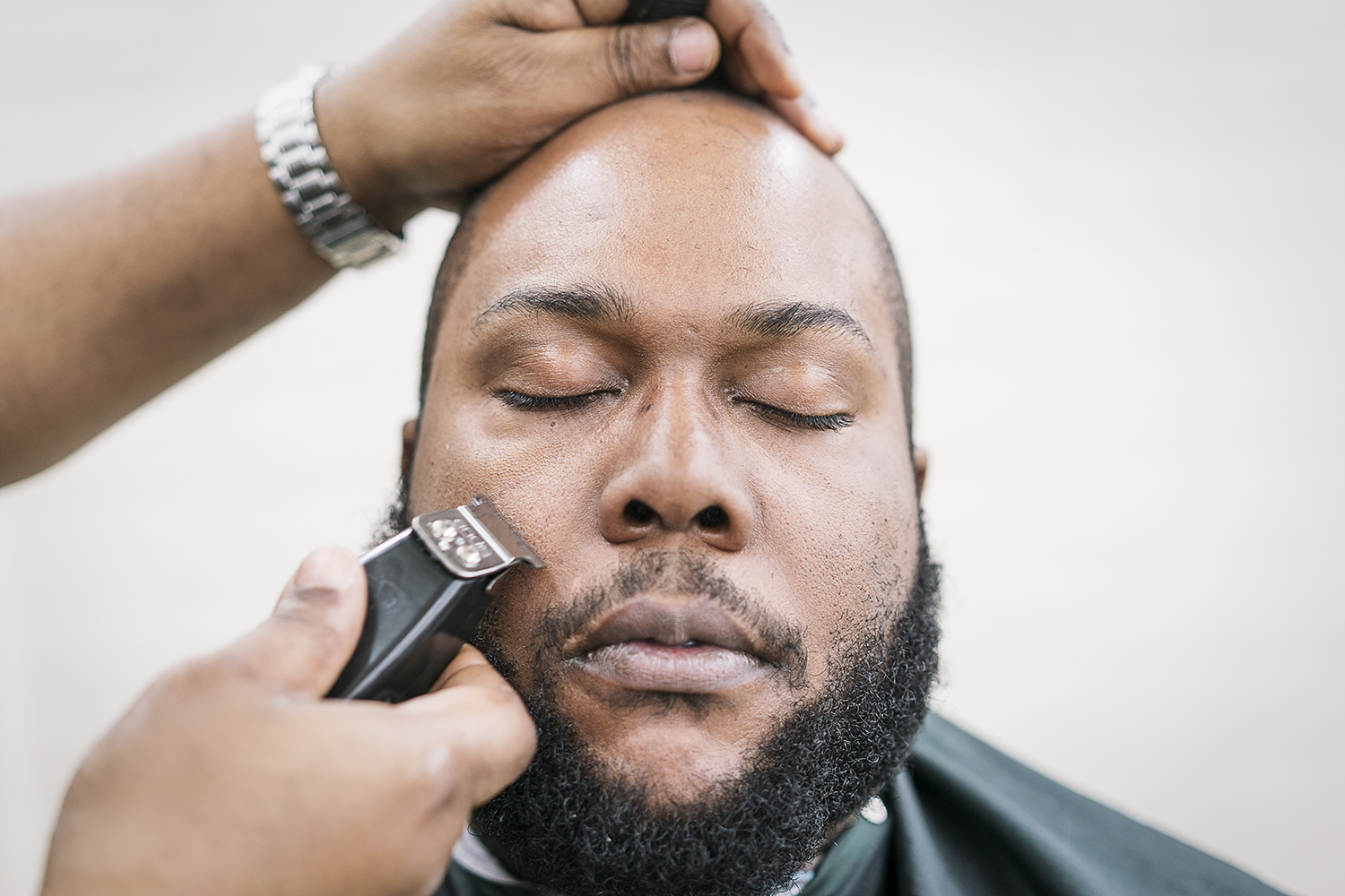Flint, MI - Tuesday, February 6, 2018: Flint resident Brandon Ashley, 34, closes his eyes and relaxes while he receives a haircut and beard trim at the Flint Institute of Barbering.