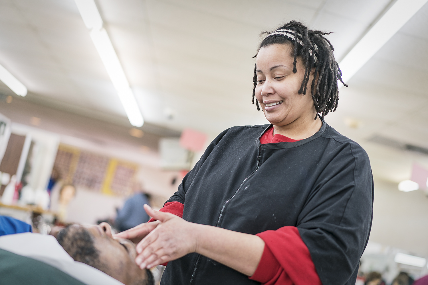 Flint, MI - Tuesday, February 6, 2018: Burton resident Altovise Wright, 38, performs a facial on classmate Terry Knapp Sr., 36, from Flint, during the slow hours of the day to practice services at the Flint Institute of Barbering.