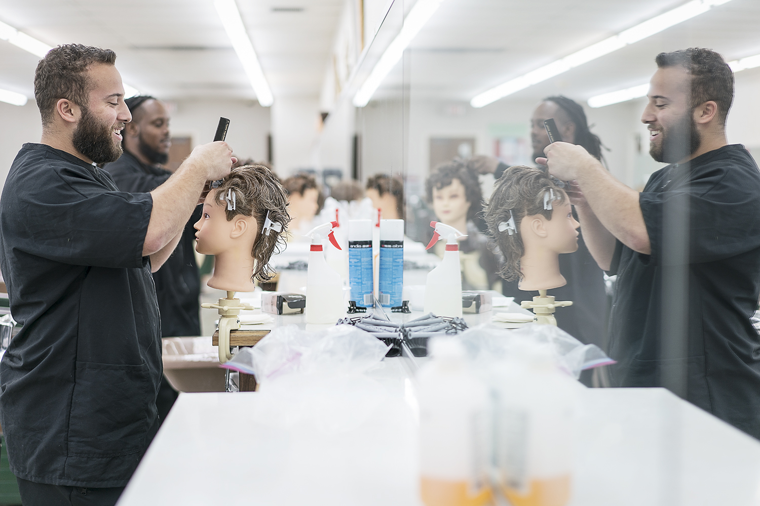 Flint, MI - Tuesday, February 6, 2018: Junior barbers Cole Stomp, 19, from Davison, and Tony Atlas, 32, from Flint practice on mannequins at the Flint Institute of Barbering.