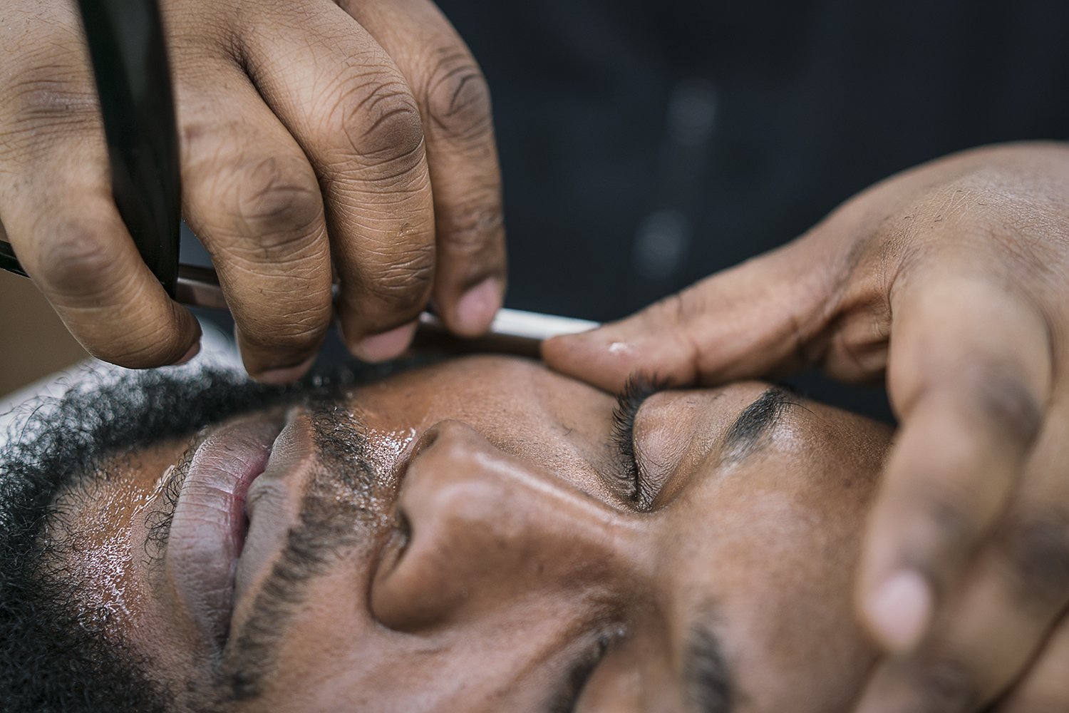 Flint, MI - Tuesday, February 6, 2018: Flint resident Brandon Ashley, 34, reclines as he is given a straight razor shave at the Flint Institute of Barbering.