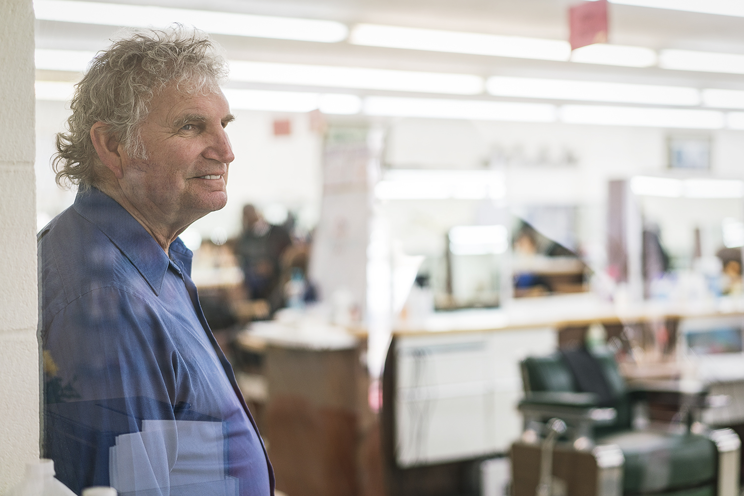 Flint, MI - Tuesday, February 6, 2018: Flint Institute of Barbering Director of Education Bob Morey, 68, from Linden, smiles as he oversees students on the floor.