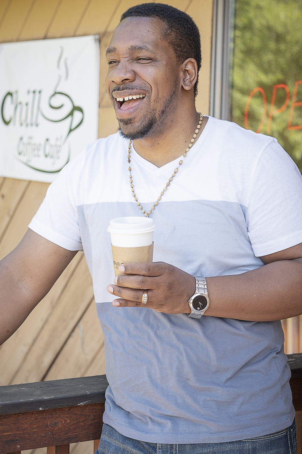 Flint, MI - Friday, June 15, 2018: Owner and pastor, Martez Warren laughs as he drinks a cup of coffee in front of Chill Coffee Cafe.