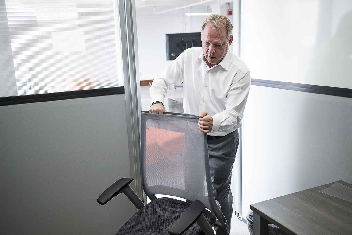 Flint, MI - Thursday, June 22, 2018: Choice Office Products president Greg Ballard (60) from Grand Blanc move an office chair into a new satellite location at The Ferris Wheel in Downtown Flint.