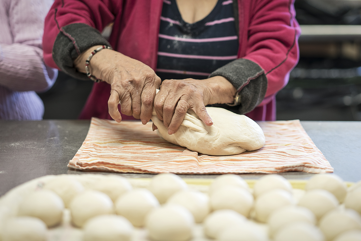 Flint resident Vina Shattuck, 70, the newest member to the group, tears apart pieces of masa to roll into small balls and flattened into tortillas in the kitchen in the San Juan Diego Activity Center at Our Lady of Guadalupe Catholic Church. 