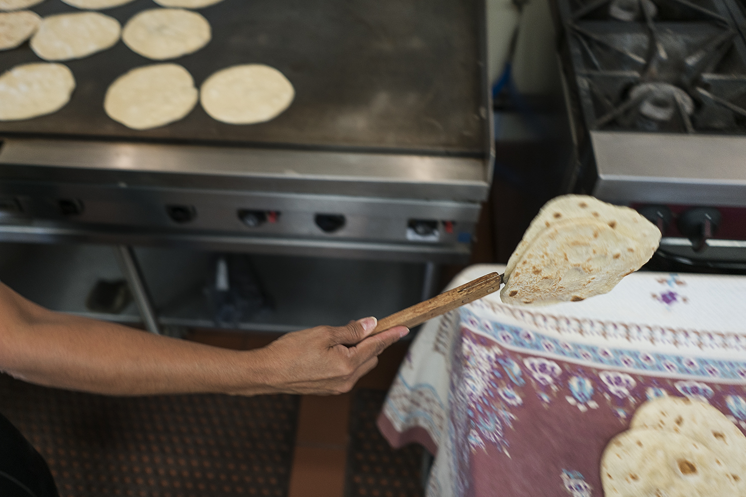 Flint resident Julia Perez-Stutso flips tortillas from the cooktop onto a cart covered with a cloth to cool before being packaged.