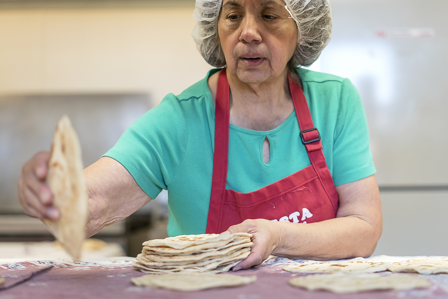 Flint resident Connie Rosas, 72, collects and stacks tortillas to be packaged after they have cooled.