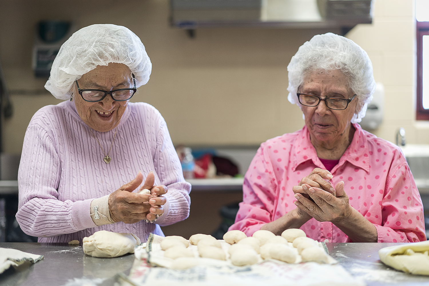 Linda Quintanilla, 90, of Flushing, (left) laughs as she rolls balls of masa and chats with Connie Aguilar, 81, of Flint, at Our Lady of Guadalupe's Tortilla Factory.
