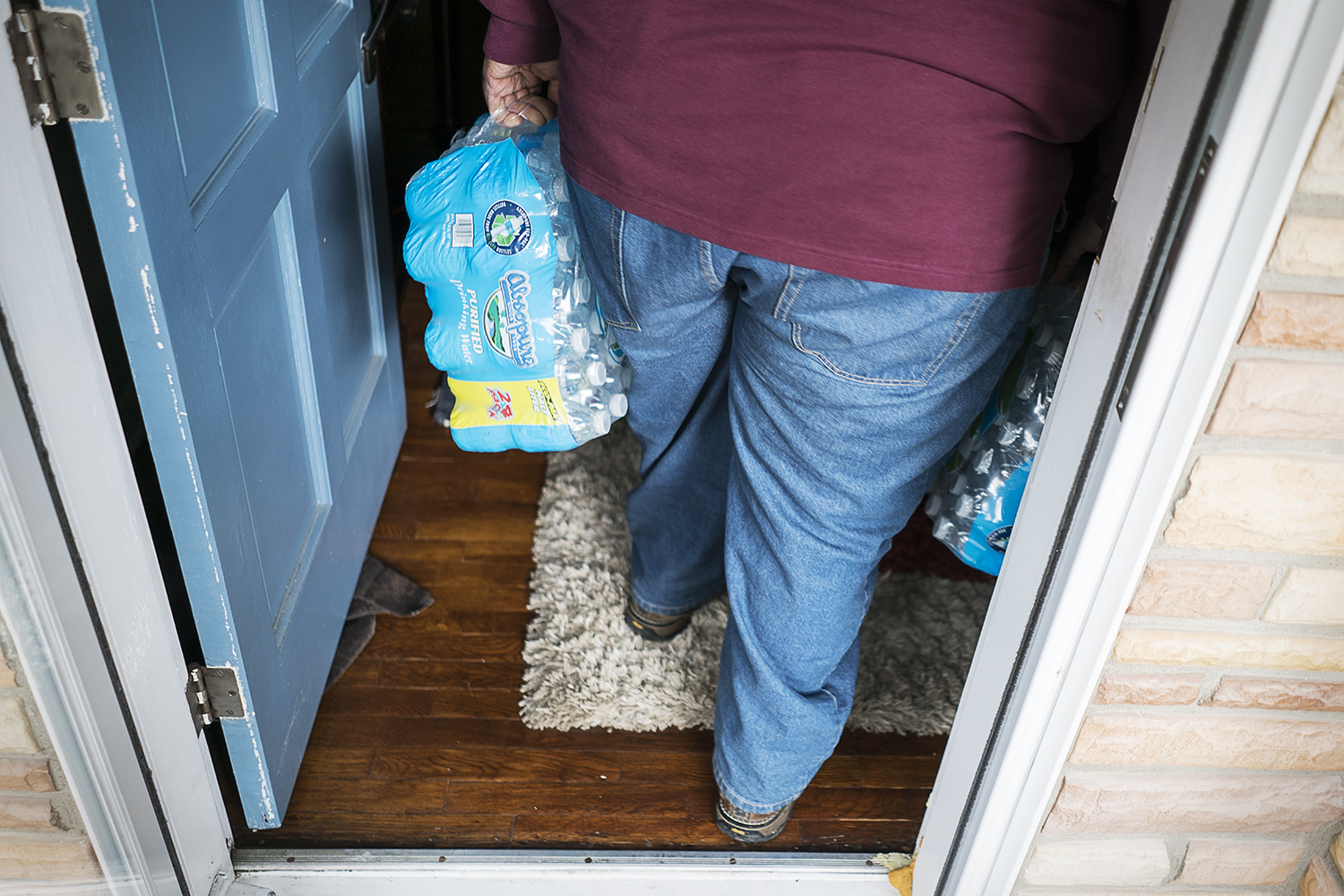 William Harris, 31, of Flint, carries two cases of water into a home of a resident in the 4th Ward. 