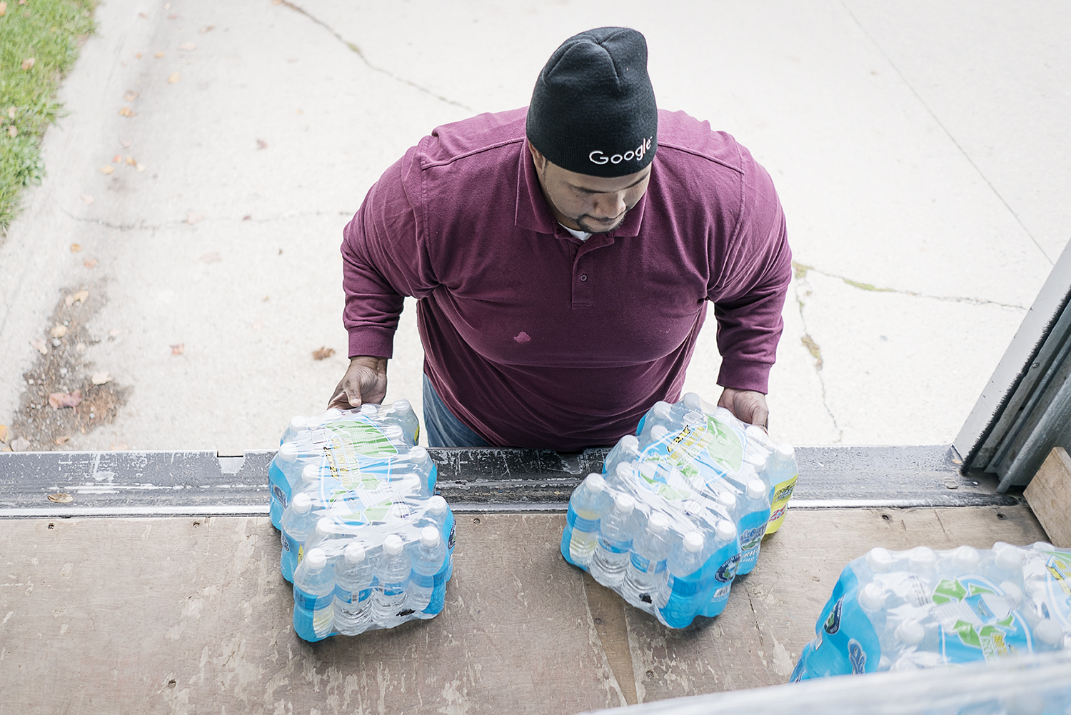 William Harris, 31, of Flint, slides two cases of water off the back of his team's delivery truck on Flint's eastside. The team from Asbury United Methodist deliver water to 60 to 70 homes on their route.
